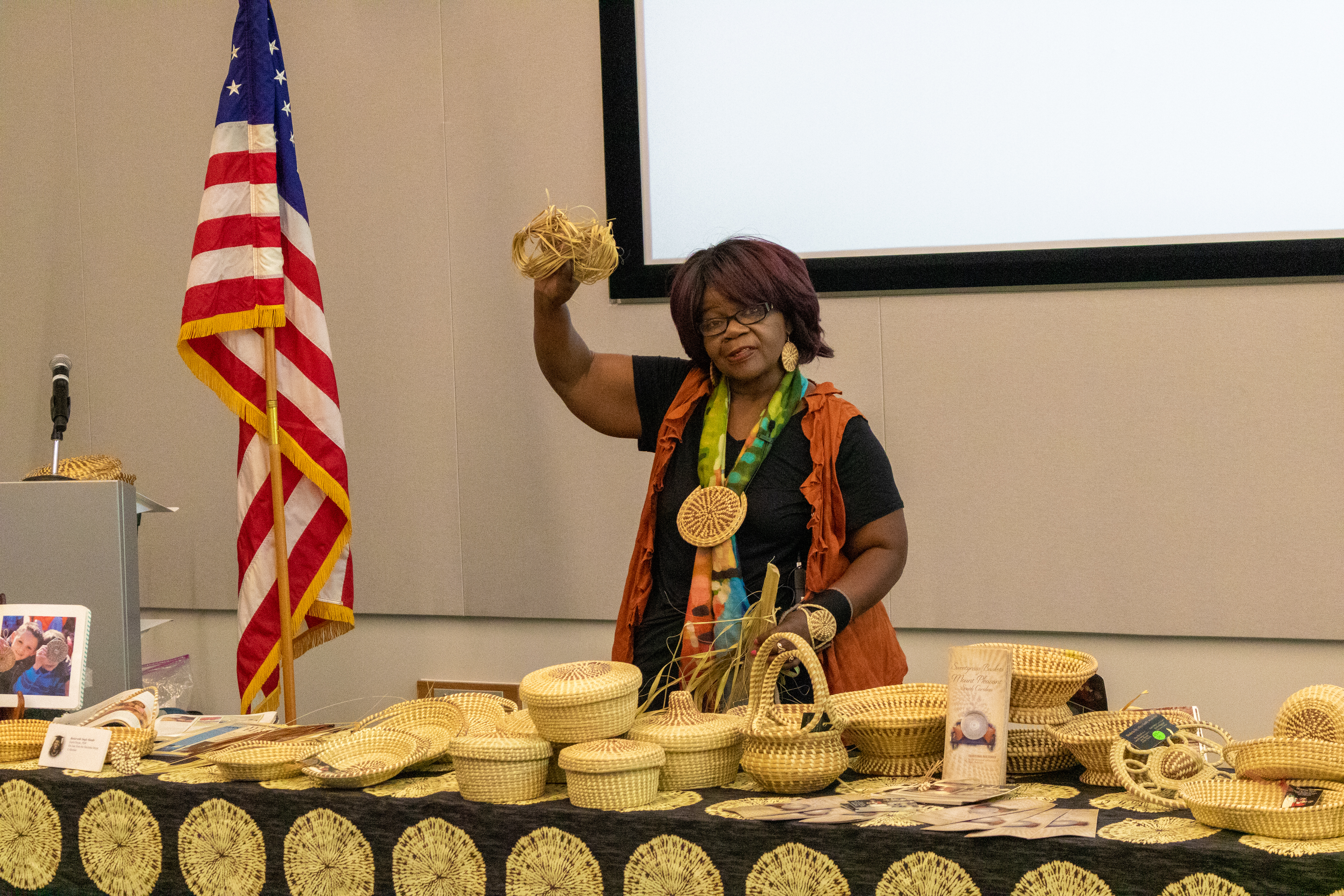 Woman standing with table of woven baskets