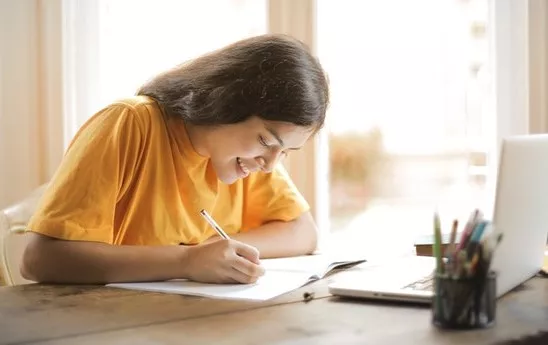woman writing notes in front of a computer