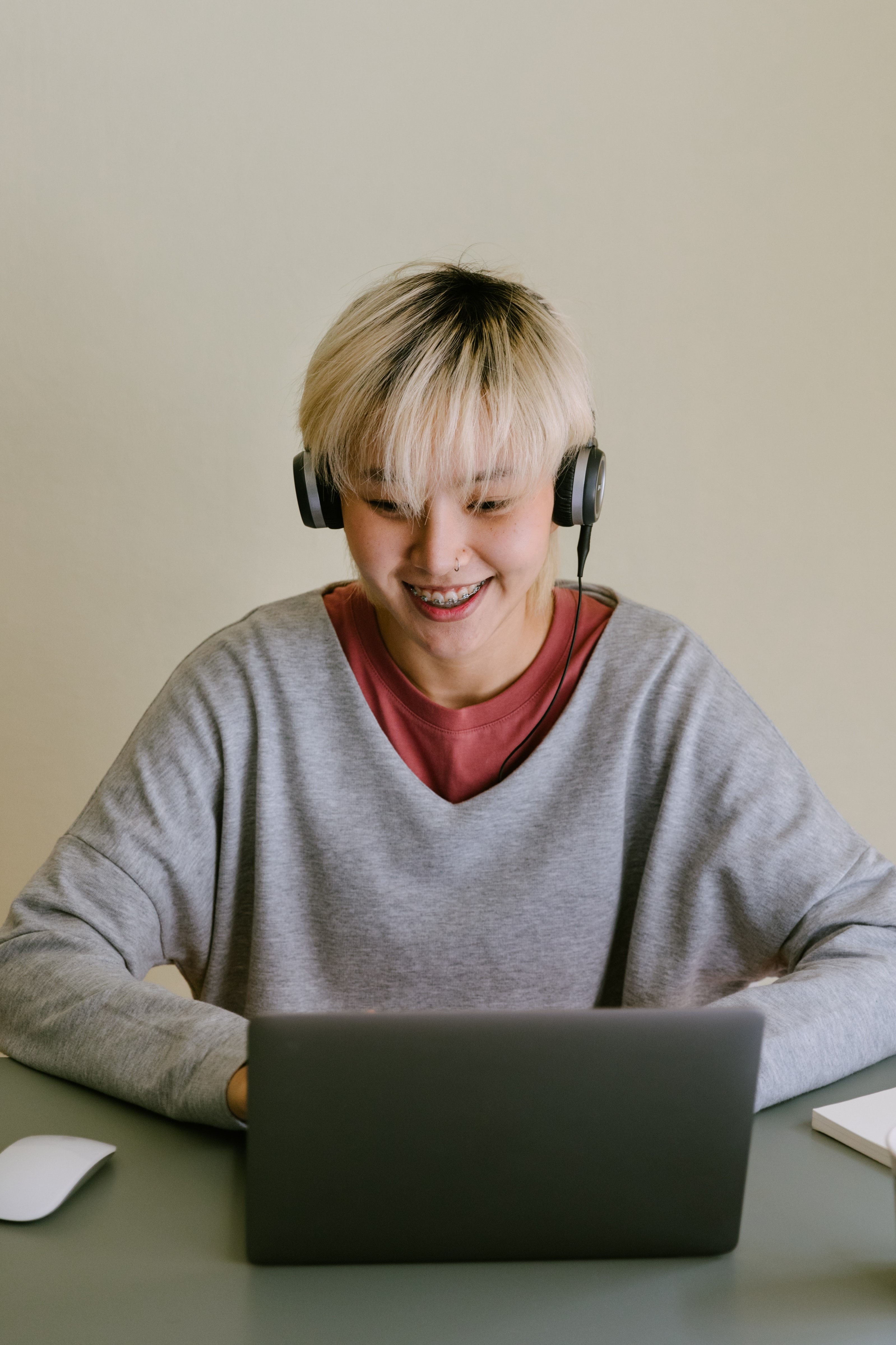 young asian woman with bleached hair and headphones at a computer